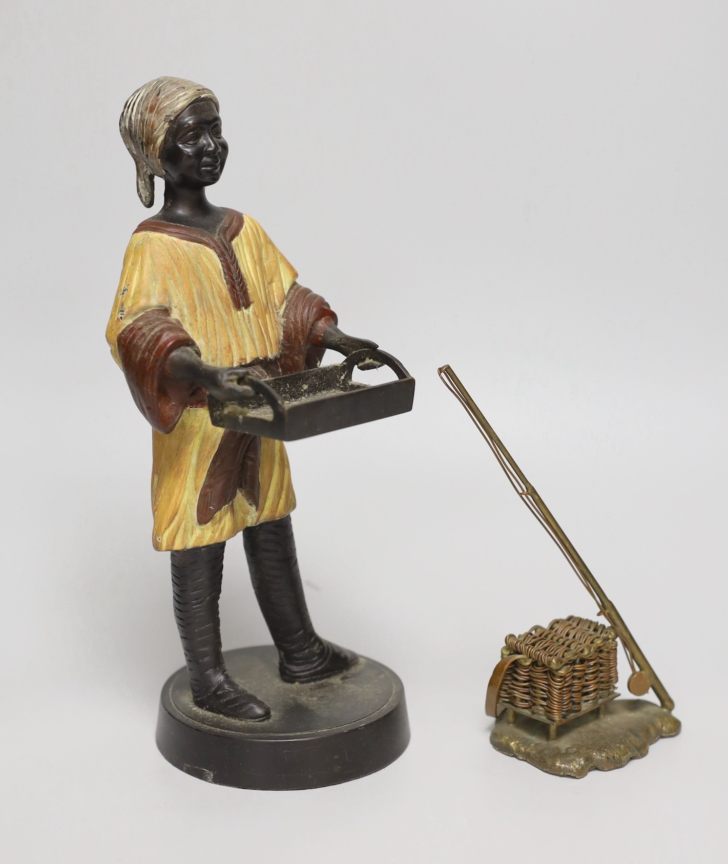 A bronzed spelter figure and cast brass fishing rod and basket, figure 27cms high